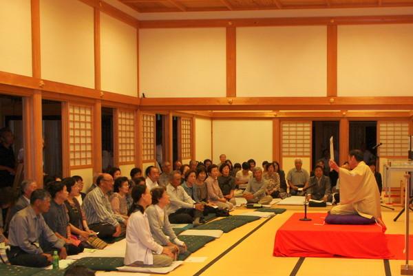 篠山城大書院の中で落語が行われ、座布団に座り落語を楽しんでいる方々の写真